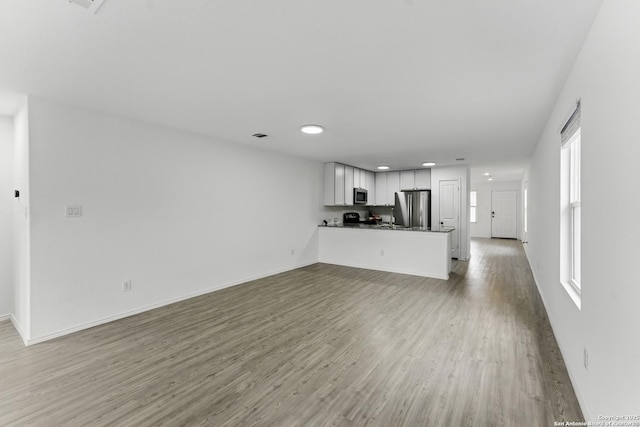 unfurnished living room featuring light wood finished floors, recessed lighting, and baseboards
