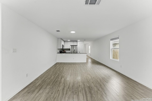 unfurnished living room with recessed lighting, visible vents, wood finished floors, and baseboards