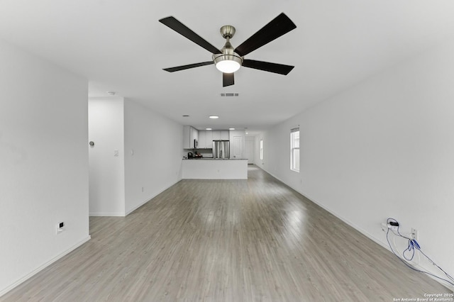unfurnished living room with light wood finished floors, a ceiling fan, visible vents, and baseboards