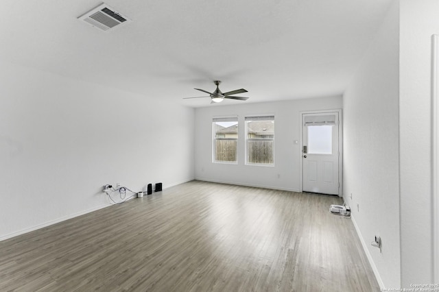 unfurnished room with wood finished floors, visible vents, a ceiling fan, and baseboards