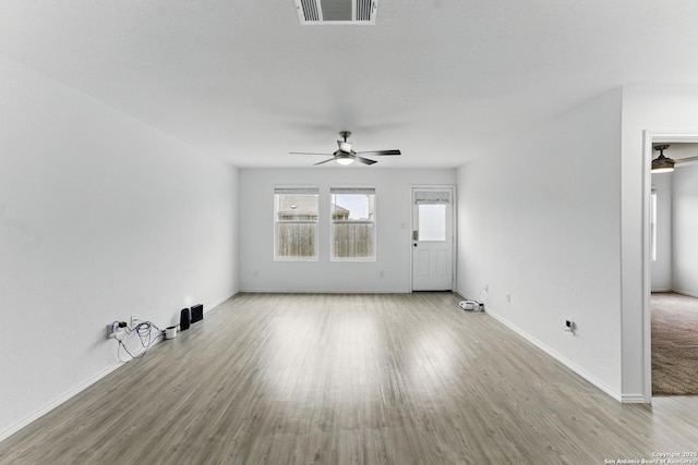 unfurnished living room with baseboards, visible vents, wood finished floors, and a ceiling fan