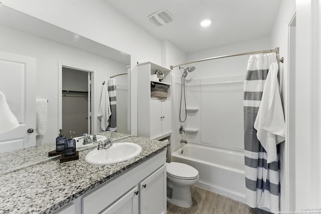 bathroom featuring visible vents, shower / tub combo with curtain, toilet, wood finished floors, and vanity