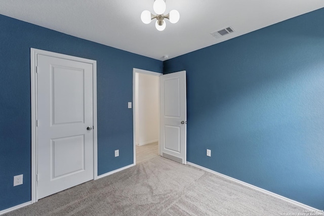 unfurnished bedroom featuring a chandelier, visible vents, carpet flooring, and baseboards