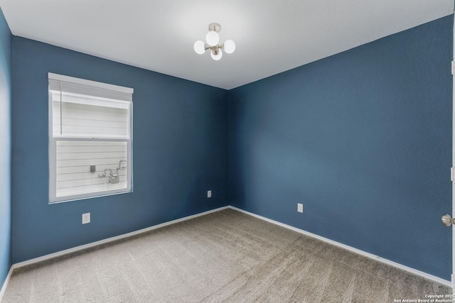 unfurnished room featuring an inviting chandelier, carpet, and baseboards