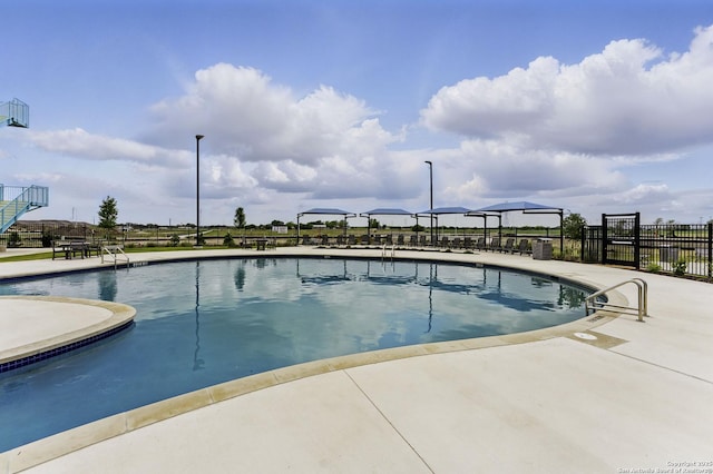 community pool with a patio and fence