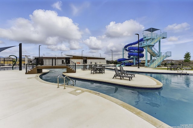 pool featuring stairway, a water slide, and a patio area