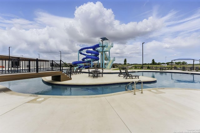 community pool featuring a patio and a water slide