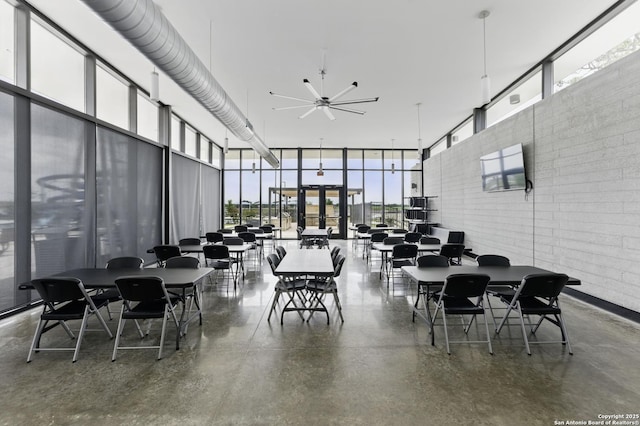 dining space featuring a towering ceiling, a ceiling fan, floor to ceiling windows, and a wealth of natural light
