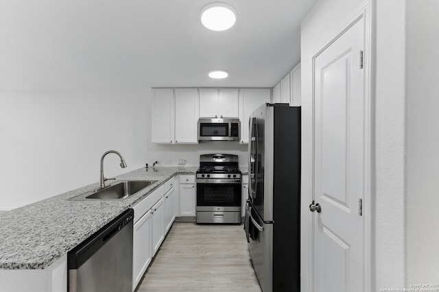kitchen featuring stainless steel appliances, white cabinets, a peninsula, and a sink