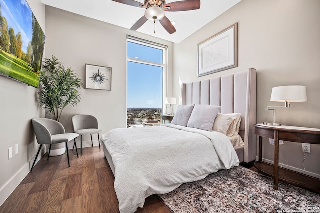 bedroom with dark wood-type flooring, a ceiling fan, and baseboards