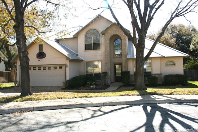 view of front facade featuring a garage, stone siding, concrete driveway, stucco siding, and fence