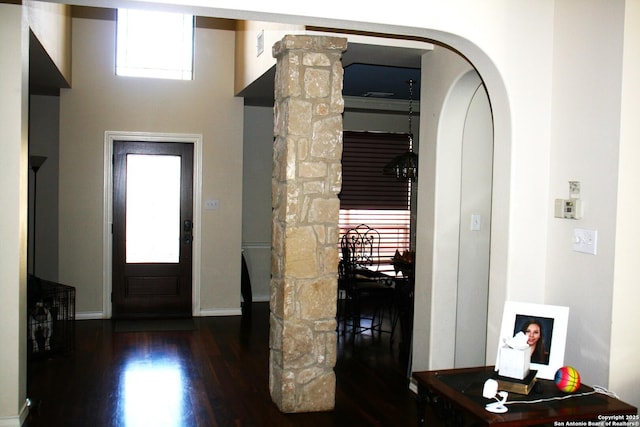 foyer entrance with baseboards, wood finished floors, and ornate columns