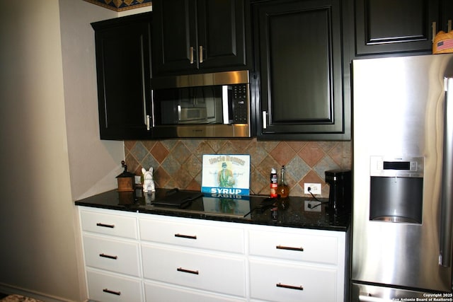kitchen with appliances with stainless steel finishes, tasteful backsplash, dark cabinetry, and dark stone countertops
