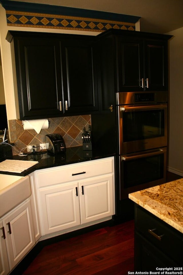 kitchen with tasteful backsplash, white cabinetry, double oven, dark cabinetry, and dark wood-style floors