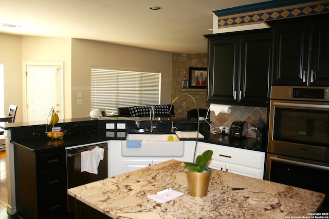 kitchen with dark cabinets, decorative backsplash, double oven, a sink, and visible vents