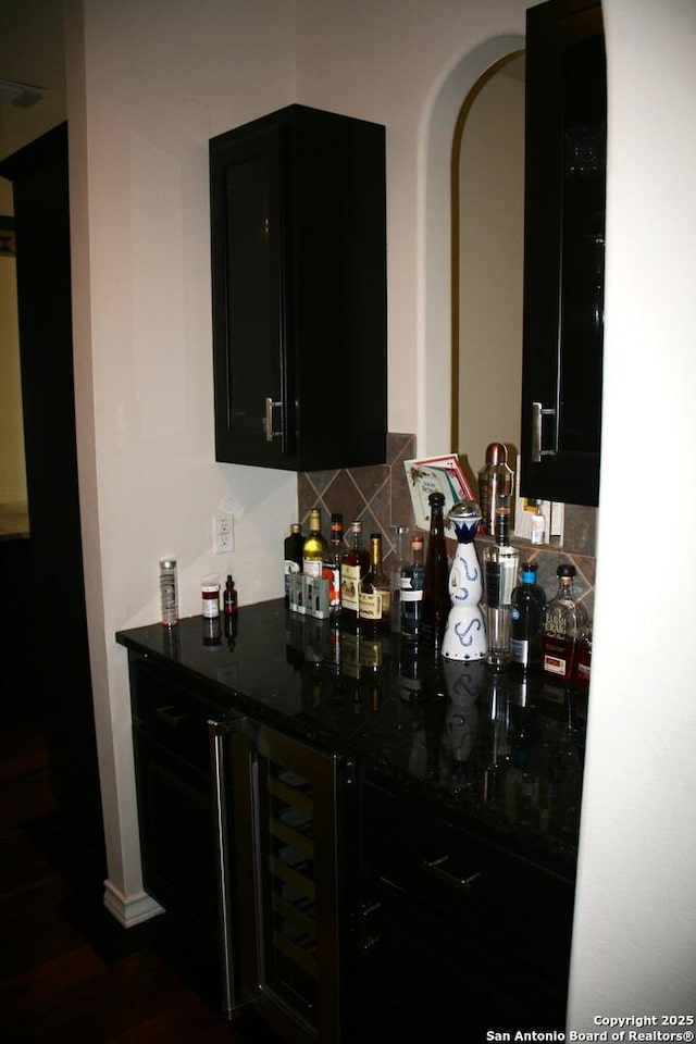 bar with beverage cooler, arched walkways, decorative backsplash, visible vents, and a bar