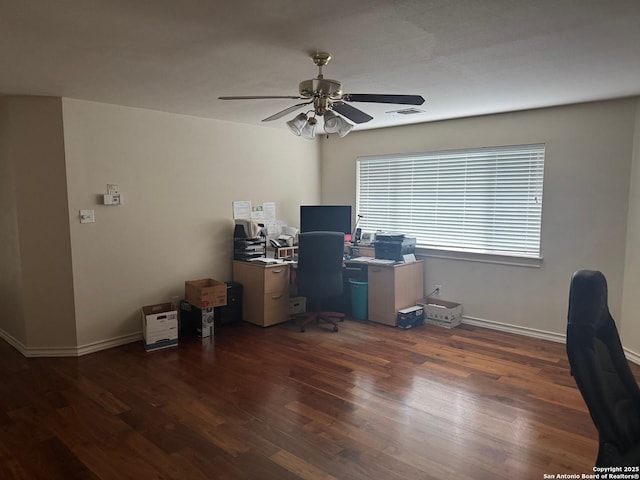 home office featuring dark wood-style floors, a ceiling fan, visible vents, and baseboards