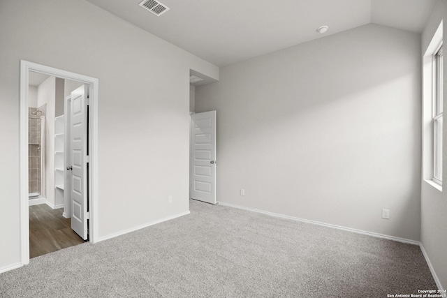 unfurnished bedroom with carpet flooring, visible vents, baseboards, lofted ceiling, and a spacious closet