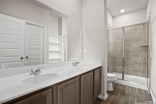 full bathroom with wood finished floors, toilet, a shower stall, and a sink