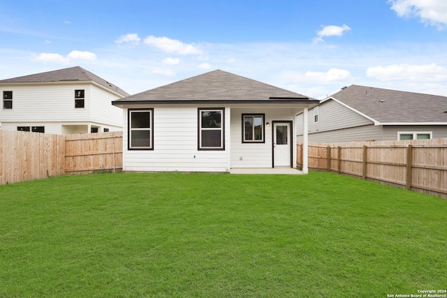 rear view of house featuring a yard, a fenced backyard, and roof with shingles