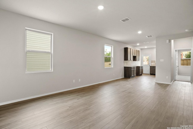 unfurnished living room with recessed lighting, visible vents, wood finished floors, and plenty of natural light