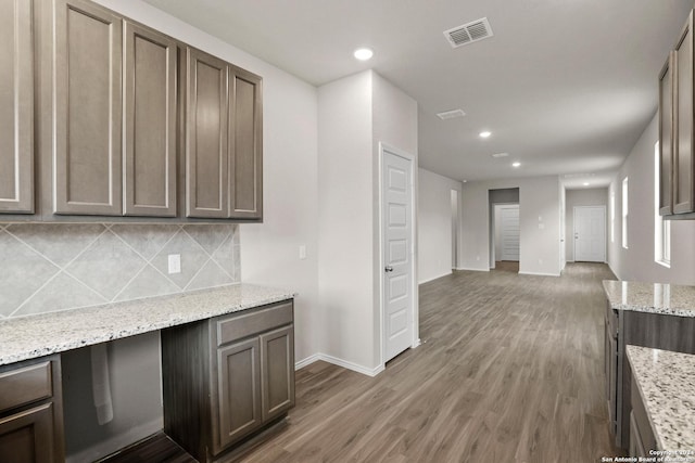 kitchen featuring visible vents, wood finished floors, decorative backsplash, and baseboards