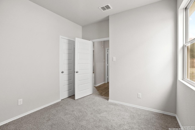 unfurnished bedroom featuring carpet flooring, visible vents, multiple windows, and baseboards