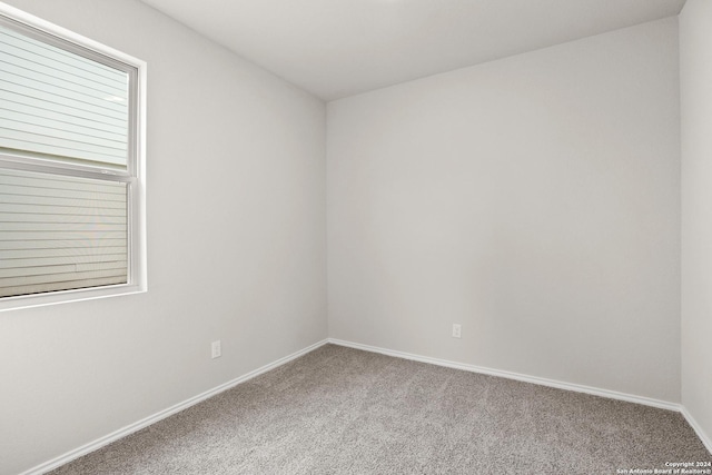 carpeted spare room featuring baseboards
