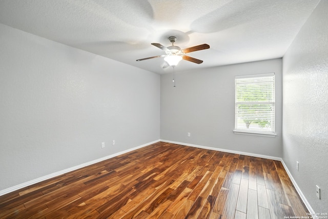 spare room featuring a textured ceiling, a ceiling fan, dark wood finished floors, and baseboards