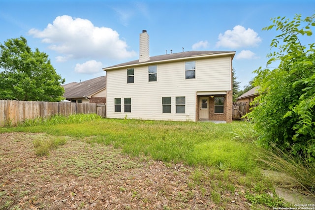 rear view of property featuring a fenced backyard and a chimney