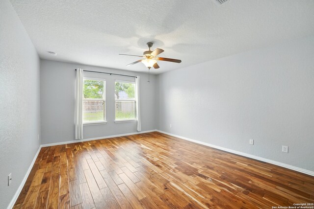 unfurnished room featuring a textured ceiling, ceiling fan, wood finished floors, and baseboards