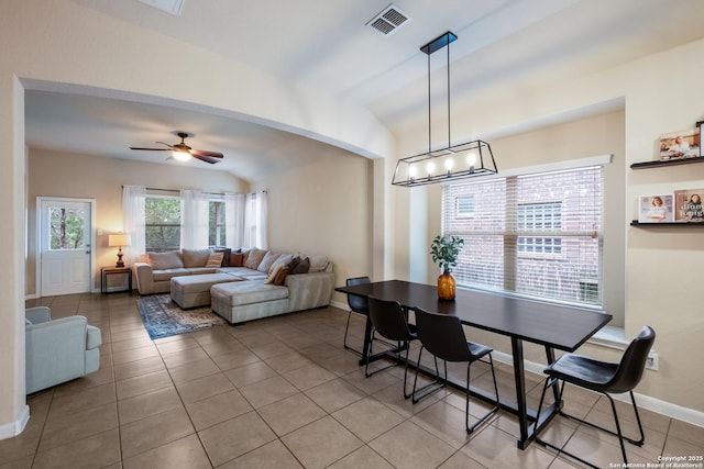 dining space with light tile patterned floors, visible vents, arched walkways, vaulted ceiling, and ceiling fan with notable chandelier