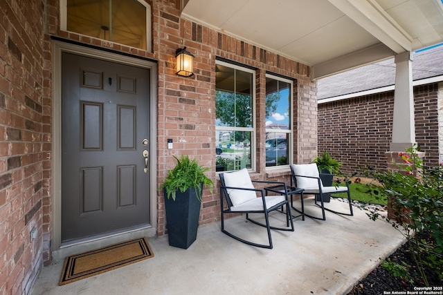 property entrance featuring a porch and brick siding