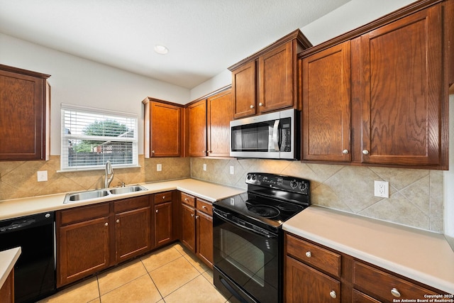 kitchen with a sink, light countertops, black appliances, light tile patterned flooring, and backsplash