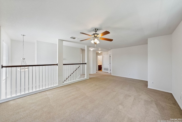 carpeted empty room with visible vents, baseboards, and ceiling fan with notable chandelier