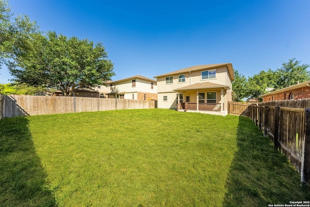 rear view of house with a lawn and a fenced backyard