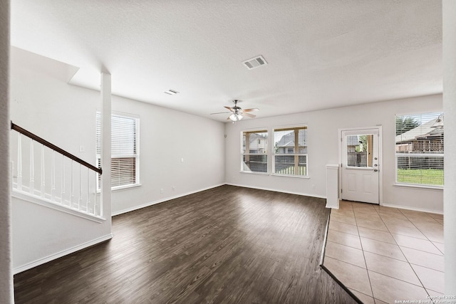 unfurnished living room with stairs, visible vents, ceiling fan, and wood finished floors