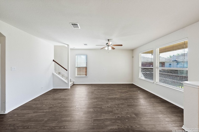 unfurnished living room with wood finished floors, stairway, ceiling fan, baseboards, and visible vents