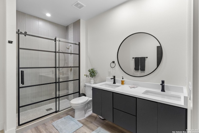 bathroom featuring toilet, a sink, a shower stall, and wood finished floors