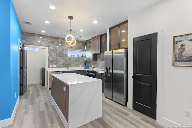 kitchen featuring a sink, a center island, visible vents, light countertops, and appliances with stainless steel finishes