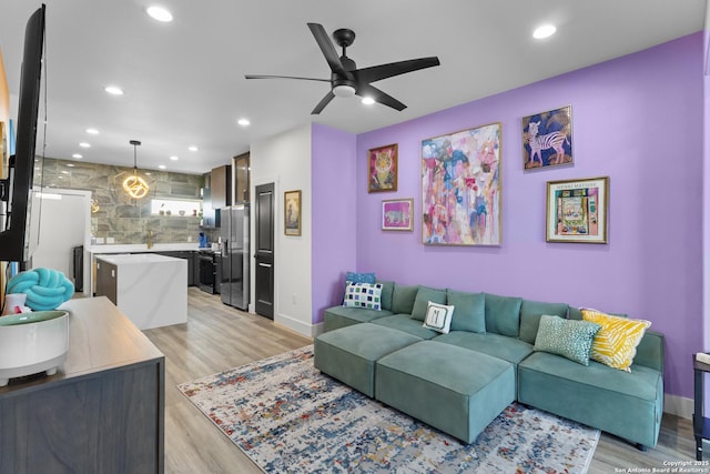 living area with baseboards, recessed lighting, ceiling fan, and light wood-style floors