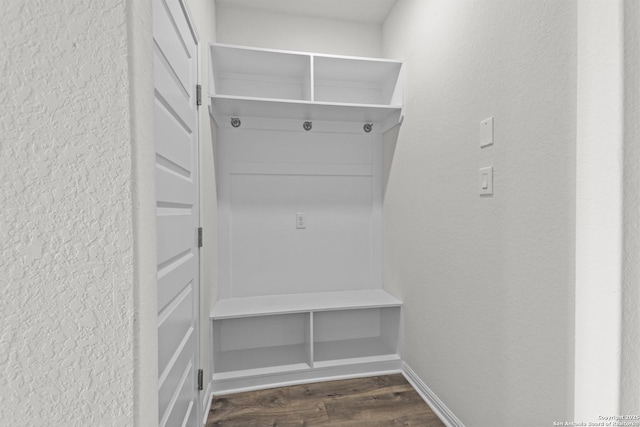 mudroom featuring dark wood-style flooring, a textured wall, and baseboards