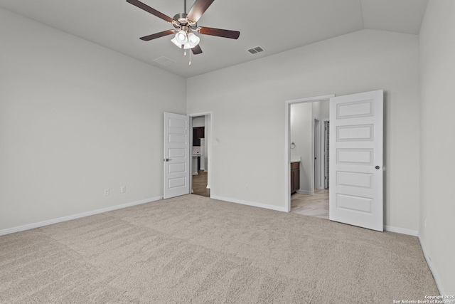 unfurnished bedroom featuring light carpet, vaulted ceiling, baseboards, connected bathroom, and ceiling fan