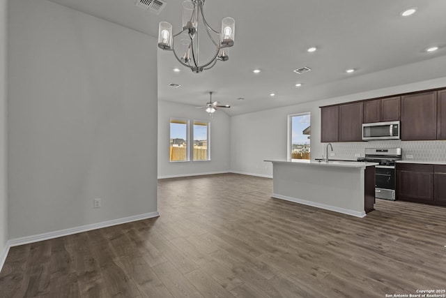 kitchen featuring appliances with stainless steel finishes, open floor plan, a chandelier, tasteful backsplash, and dark wood-type flooring