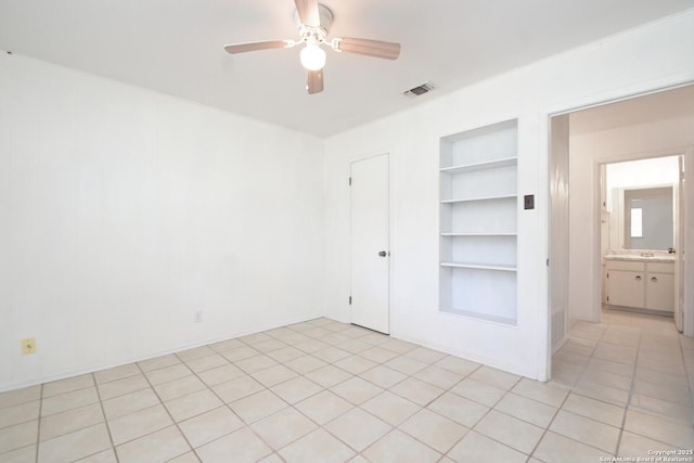 spare room with built in shelves, visible vents, and ceiling fan