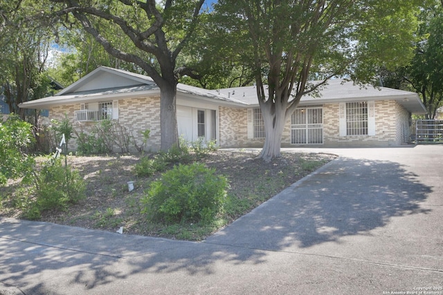 ranch-style home featuring concrete driveway and brick siding