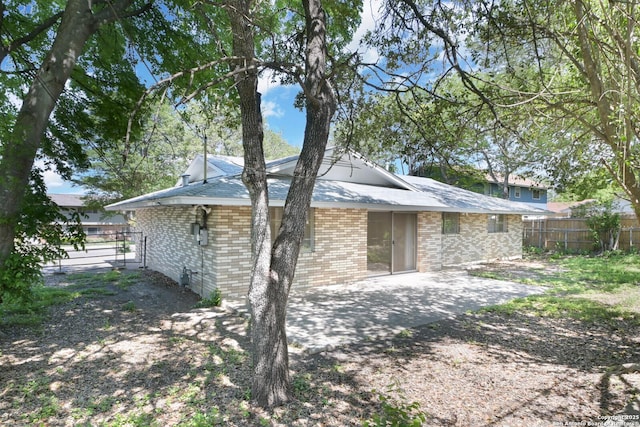 rear view of property with brick siding, a patio area, and fence