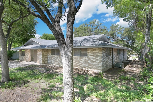 view of side of property featuring brick siding and cooling unit