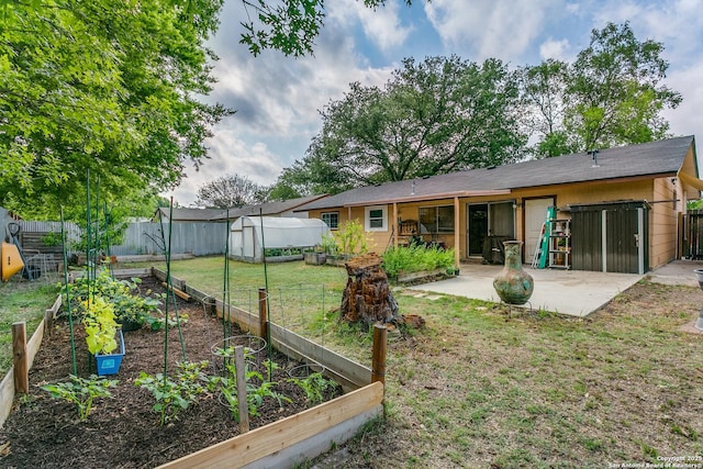 6835 Spring Hurst, San Antonio, TX 78249 - back of house with an outdoor structure, a patio, a greenhouse, a vegetable garden, and a lawn