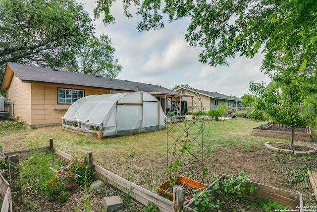 6835 Spring Hurst, San Antonio, TX 78249 - rear view of property with fence, an outbuilding, a lawn, an exterior structure, and a vegetable garden